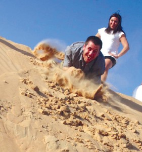 Josh sandboards on a dune while Kari looks on during their desert safari trip. Photo courtesy (Webster) Reporter & Farmer