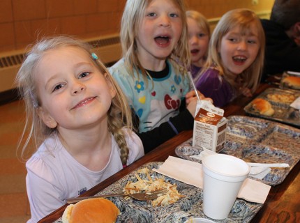 Sophia Taszarek, Isabelle Jones, and Addison Rolof smile at the lunch table at Kulm Public School. Photo by Sarah Gackle.