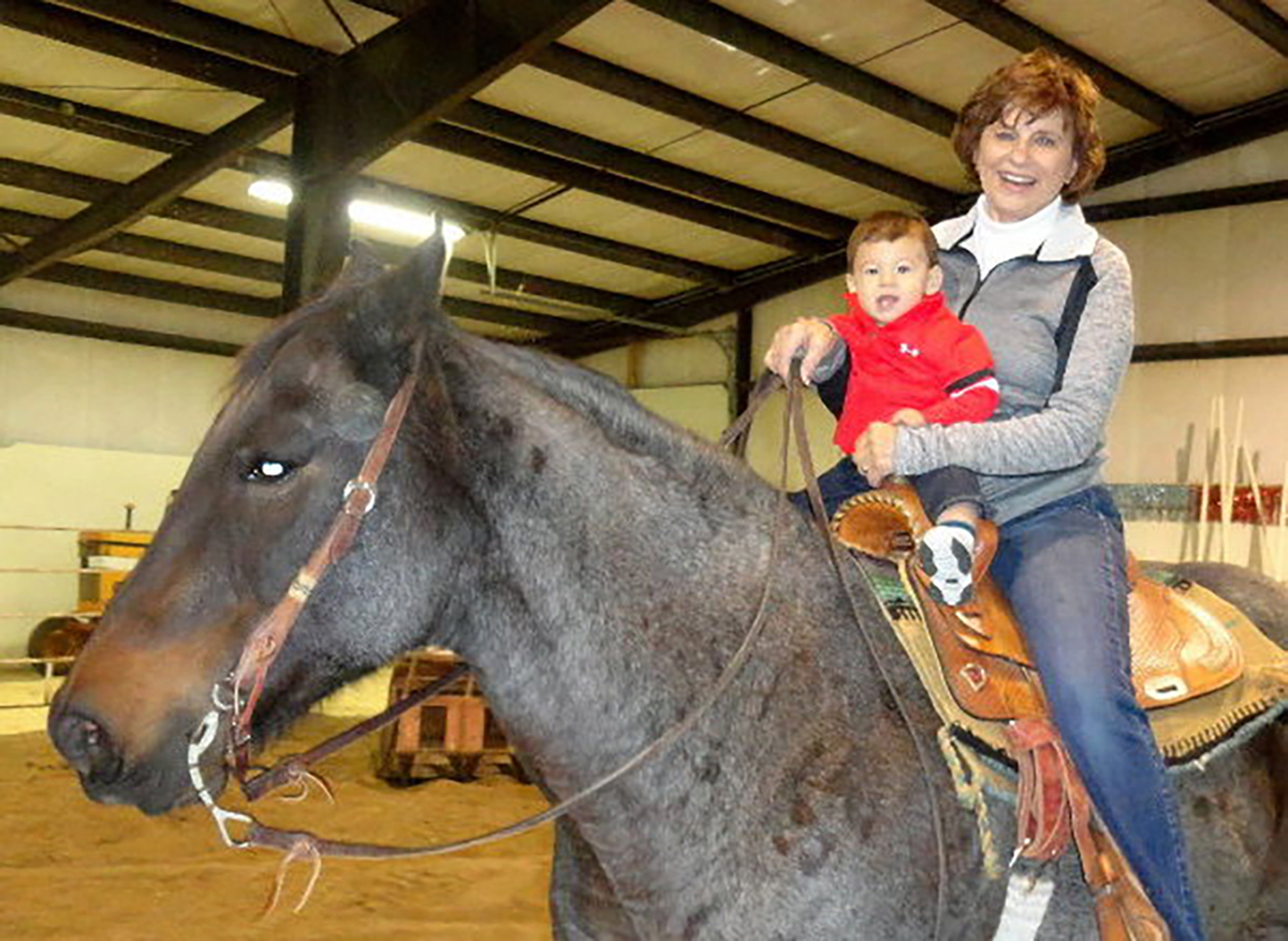 Cleone Uecker, pictured with her grandson during his first horseback ride, has owned South Dakota Horse Sales in Corsica since the late 1980s.