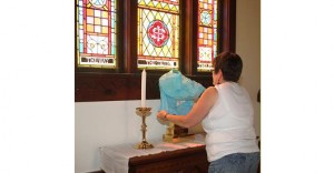 Carol White covers up the cross and candles on the altar of Trinity Episcopal Church in Groton, S.D. Photo by Groton Independent