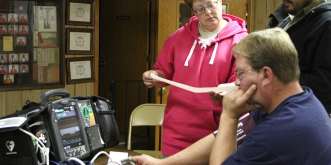 Members of Gackle Ambulance learn how to use a new EKG purchased with Mission Lifeline grant funding. South Dakota went through this program previously, and it is now being introduced in North Dakota. Pictured are, standing, Tammy Koenig and James Owen, and seated, George Koenig. Ongoing training for ambulance crews is often done in rural communities; a new proposal would encourage more online training for basic EMT skills, which would reduce the need to drive to a larger community for training. Photo by Tri-County News.