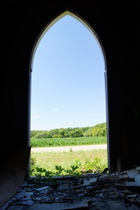 The doorway of the old church frames the farm scene across the road. Photo by Troy Larson