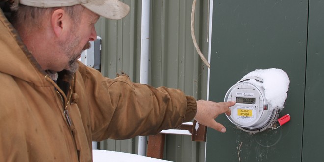 Jeff Enzminger shows the dual electrical meter at their facility. Prior to the solar panels being placed, the business purchased a daily average of 150 kw from the electrical company. After solar panels they have cut purchased electricity by two-thirds. Photo by Melody Owen