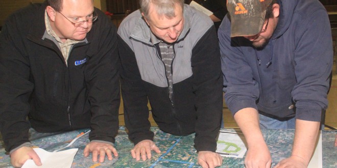 Monte Sippel, Bob Walter and TJ Harder look over the maps of the proposed route. Photo by Paul Kosel/Groton Daily Independent
