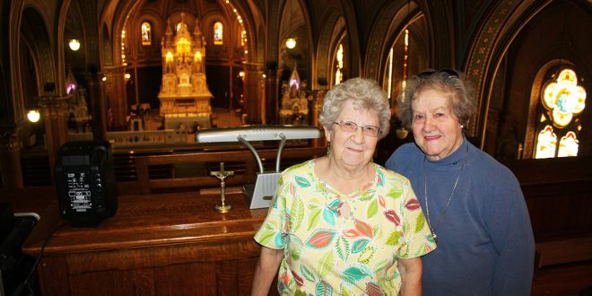 Sisters Alice Simon, left, and RoseMarie Reuer have celebrated family and community milestones in St. Anthony of Padua Catholic Church for six generations. They and deceased sister Agnes Reuer have proudly hosted numerous tours of the “Cathedral on the Prairie.” By Wendy Roston/Dakotafire Media